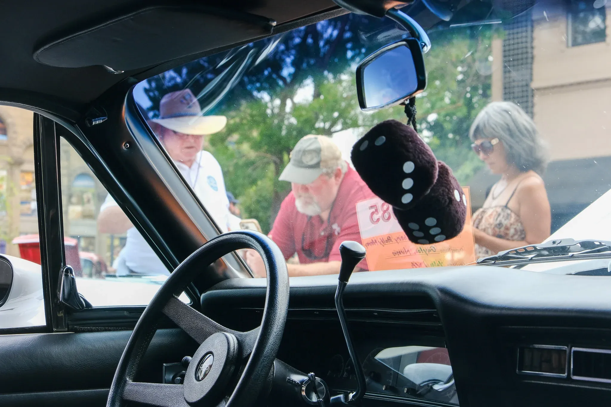 Attendees inspect classic sedans — fuzzy dice hanging from several — during Wheelin' Walla Walla.